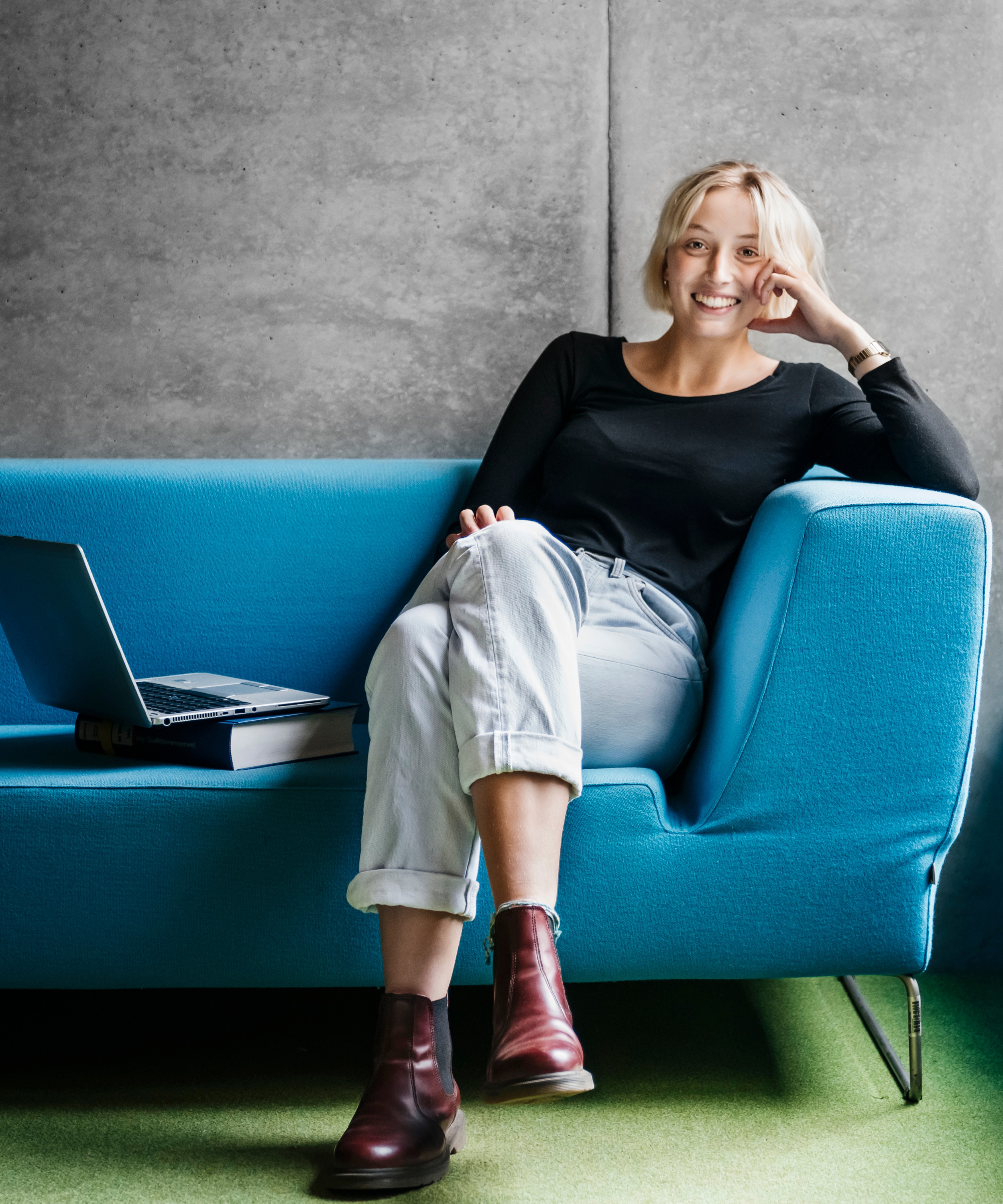 Frau sitzt lächelnd auf einem blauen Sofa